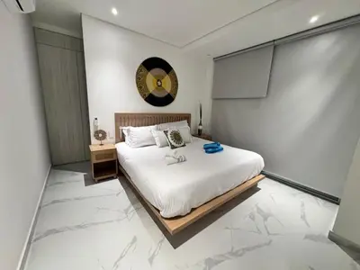 a bedroom with a large white bed with a clock on the wall at Santa marta bello horizonte Swift Lotf in Playa Bello Horizonte