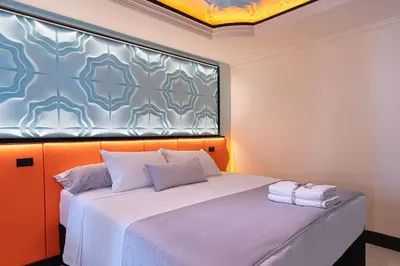 a bedroom with a large bed with an orange wall at Casa Stella Rooms in Cartagena de Indias