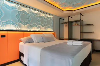 a bedroom with a large white bed with an orange wall at Casa Stella Rooms in Cartagena de Indias