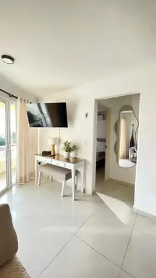 a white living room with a table and a mirror at Cabrero Beach 507 in Cartagena de Indias