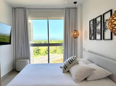 a bedroom with a large white bed with a large window at Hermoso apartamento familiar in Cartagena de Indias