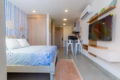 a bedroom with a bed and a tv and a kitchen at Apartamento con playa y piscina a 5 minutos del aeropuerto in Santa Marta