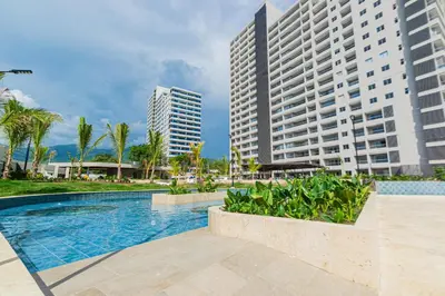 a swimming pool in front of two tall buildings at Apartamento con playa y piscina a 5 minutos del aeropuerto in Santa Marta