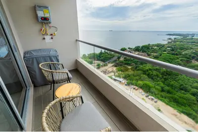 a balcony with a table and chairs and the ocean at Apartamento con playa y piscina a 5 minutos del aeropuerto in Santa Marta