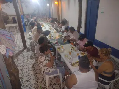a group of people sitting at long tables eating food at Playas el paraiso in San Bernardo del Viento
