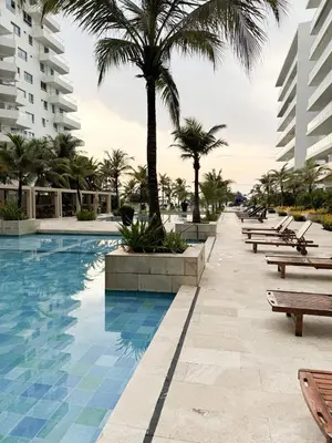 a resort swimming pool with benches and palm trees at Apartamento en Cartagena con balcón en Morros in Cartagena de Indias