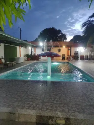 a pool with an umbrella and a fountain at Cabaña villa in Sabanagrande