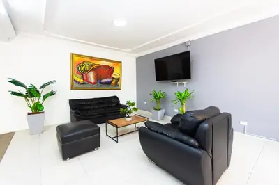 a living room with black leather furniture and a flat screen tv at Hotel Costa Caribe BAQ in Barranquilla