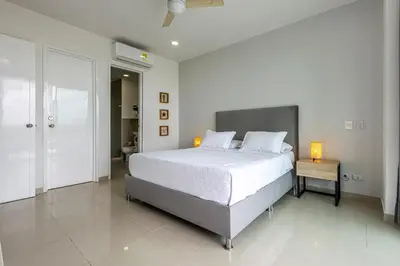a white bedroom with a large bed and a table at 224 - Morros Epic Acceso Directo a Playa in Cartagena de Indias