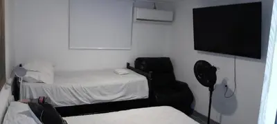 a room with two beds and a chair and a flat screen tv at apartamento 3 habitaciones totalmente equipado in Cartagena de Indias
