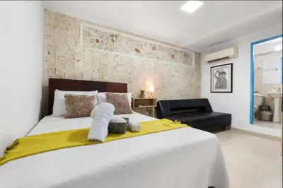 a bedroom with a large white bed with a yellow blanket at Casa Mary Hotel in Cartagena de Indias