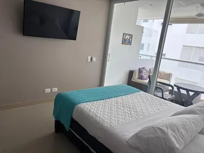 a bedroom with a bed and a flat screen tv at Apto con playa, hotel y piscina in Santa Marta