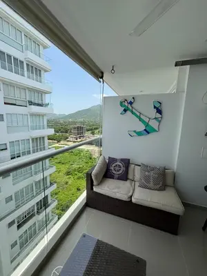 a balcony with a couch and a large window at Apto con playa, hotel y piscina in Santa Marta