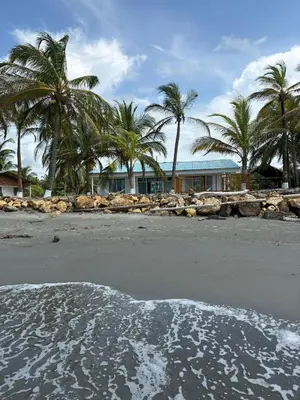 a beach with palm trees in front of a house at San Bernardo del Viento Cabaña La Isabela in San Bernardo del Viento