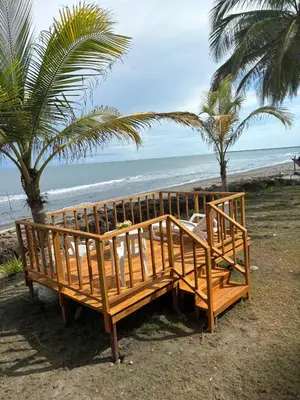 a wooden bench on the beach with palm trees at San Bernardo del Viento Cabaña La Isabela in San Bernardo del Viento