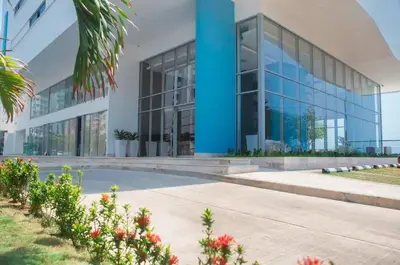 a large glass building with flowers in front of it at Oceanview Bocagrande Laguito Palmetto Sunset Building in Cartagena de Indias
