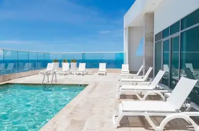 a pool on the roof of a building with white lounge chairs at Oceanview Bocagrande Laguito Palmetto Sunset Building in Cartagena de Indias