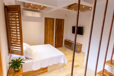 a bedroom with a white bed and a tv at Blue House Castillo View Private Jacuzzi & Colonial Balconies in Cartagena de Indias