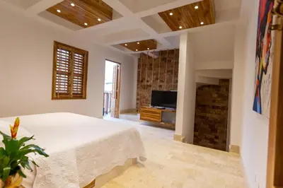 a bedroom with a large white bed and a television at Blue House Castillo View Private Jacuzzi & Colonial Balconies in Cartagena de Indias
