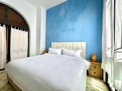 a bedroom with a white bed and a blue wall at Calamari Homes - El Porvenir 305 - Walled city in Cartagena de Indias