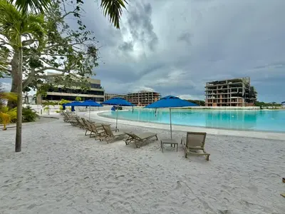 a beach with chairs and blue umbrellas and a pool at Baia Krystal P4, 1A in Cartagena de Indias