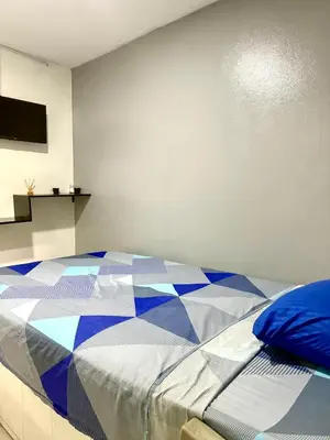 a bedroom with a bed with a blue and white quilt at Hotel las nubes Barranquilla in Barranquilla