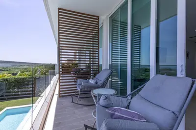 a balcony with two chairs and a table and a pool at Brand new 4BR Villa at Calablanca in Cartagena de Indias