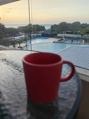 a red coffee cup sitting on a table next to a window at Apartamento con vista al mar y acceso a la playa in Santa Marta