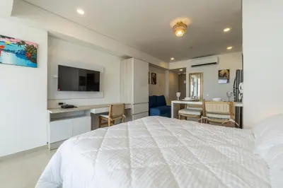 a white bedroom with a white bed and a desk at CB Lujoso Apartasuit -Vista al mar-linda piscina-cerca al Aeropuerto in Cartagena de Indias