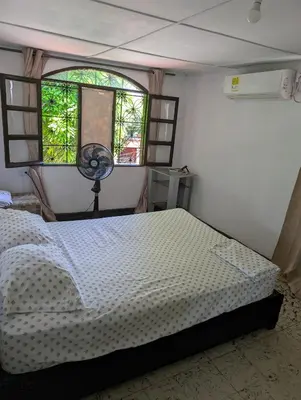 a bedroom with a bed and a window and a fan at English power Exotic point in Barranquilla