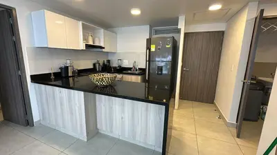 a kitchen with a black counter and a refrigerator at Apartamento cómodo en Conjunto residencial Castelo Cartagena in Cartagena de Indias