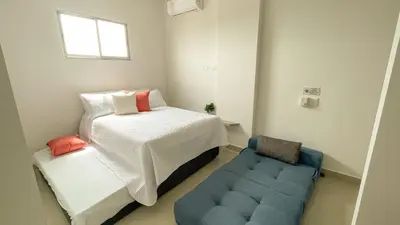 a small bedroom with a bed and a blue chair at Magico Apartamento Frente al Mar 3 Habitaciones BM91 in Coveñitas