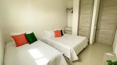 two beds in a room with white sheets and colorful pillows at Magico Apartamento Frente al Mar 3 Habitaciones BM91 in Coveñitas