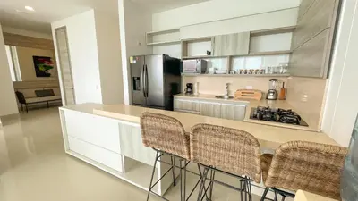a kitchen with a counter with chairs and a refrigerator at Magico Apartamento Frente al Mar 3 Habitaciones BM91 in Coveñitas