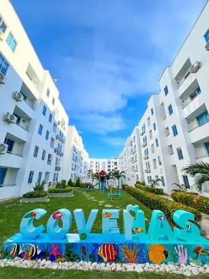 a park in front of apartment buildings with a sign that reads condos at Caribe Familiar 504 in Coveñas