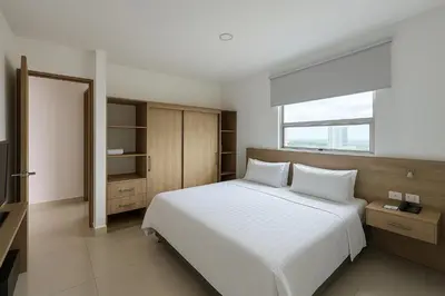 a bedroom with a large white bed and a window at Sky Collection Lifestyle Hotel & Suites Barranquilla in Barranquilla