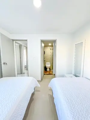 two beds in a white room with a bathroom at Azul Caribe 104 in Coveñas