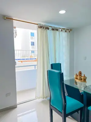 a dining room with a blue table and chairs and a window at Celeste Caribe 101A in Coveñas