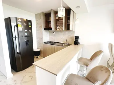 a kitchen with a refrigerator and a counter with chairs at Wow que vista!! Frente Ecoparque 7min CC Buenavista in Puerto Colombia