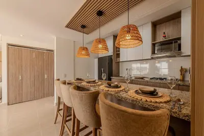 a kitchen with a long bar with chairs and lights at Condominio Moderno nuevo Trevi in Cartagena de Indias