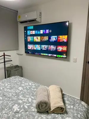 a bedroom with a bed with a tv on the wall at New modern apartment in Barranquilla