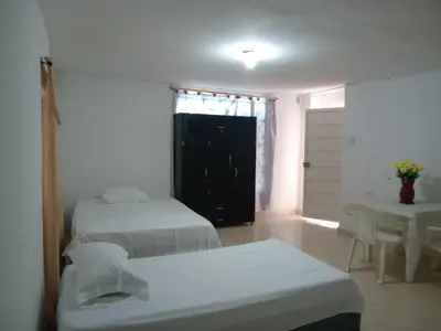 a room with two beds and a table and a window at Apartaestudio Barranquilla Calle 87 in Barranquilla