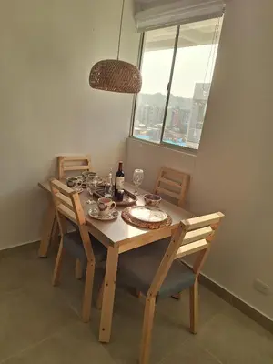 a dining room table with chairs and a bottle of wine at Cartagena playa uso exclusivo Serena del mar in Cartagena de Indias