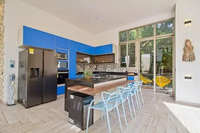 a kitchen with blue cabinets and a counter with stools at Casa BaruGrande in Cartagena de Indias