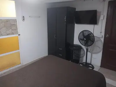 a bedroom with a black cabinet and a fan at Alojamiento independiente, sencillo y acogedor in Barranquilla