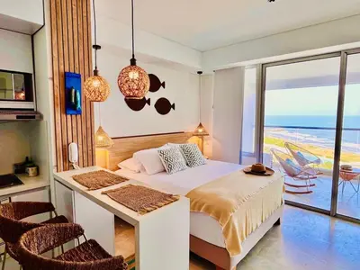 a bedroom with a bed and a desk with a view of the ocean at Beachfront Apartment - Pool - Jacuzzi - Wi-Fi in Cartagena de Indias