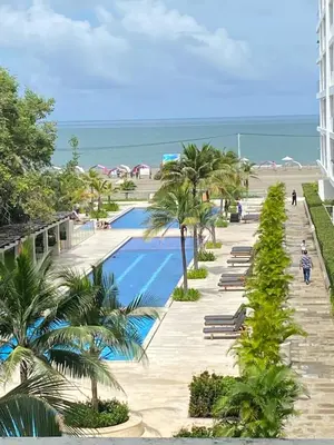a resort swimming pool with palm trees and the beach at Espectacular apartamento morros 3 in Cartagena de Indias