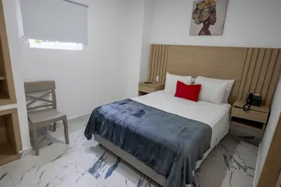 a bedroom with a bed with a red pillow at Hotel Serenity Inn in Cartagena de Indias