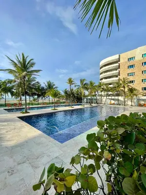 a swimming pool with palm trees and a building at Apartamento en Cartagena cerca al hotel las Américas in Cartagena de Indias