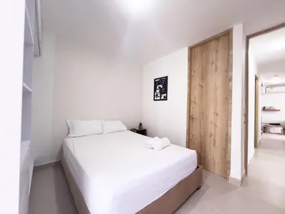 a bedroom with a white bed and a wooden door at Family apartment in Cartagena 3 bedrooms 2 bathrooms in Cartagena de Indias